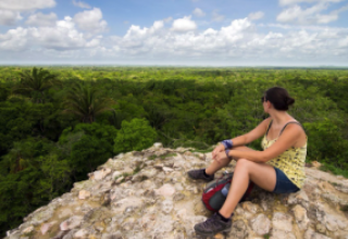 Speaker sitting on top of ruin, looking over the jungle.